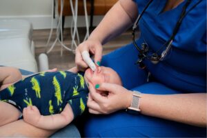 dental hygienist is using a gentle tool to examine the gums of a newborn baby